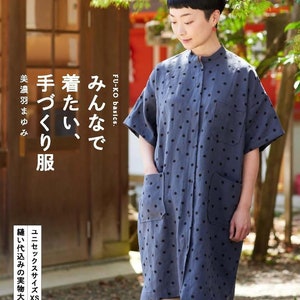 Puede incluir: Una mujer lleva un vestido de lunares azules y blancos con cuello mandarín y mangas cortas. El vestido tiene dos bolsillos en la parte delantera. El texto "FU-KO basics." y "みんなで着たい" es visible en la imagen.