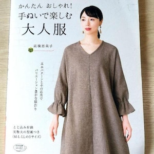 Könnte beinhalten: Ein Buchcover mit braunem Hintergrund und dem Text "かんたん おしゃれ! 手ぬいで楽しむ 大人服" in Japanisch. Das Cover zeigt eine Frau in einem braunen Kleid mit V-Ausschnitt und Rüschenärmeln.
