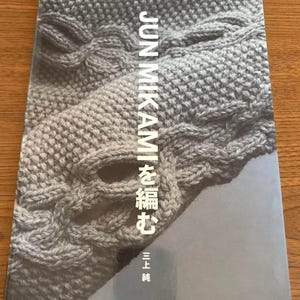 May include: A book titled "JUN MIKAMI  ami  を編む  三上  純" with a gray knitted fabric cover.