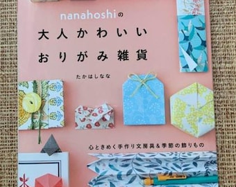 May include: A pink book with the title "大人かわいいおりがみ雑貨" (Adult Cute Origami Crafts) in Japanese. The book features colorful origami crafts, including a small box, a four-leaf clover, a chopstick holder, and a pencil holder.