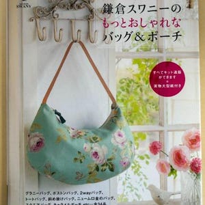 May include: A book cover featuring a teal crescent-shaped bag with a floral pattern of pink roses and green leaves. The bag hangs from a decorative hook. Japanese text is visible, along with the words "Bag & Pouch."