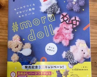 Puede incluir: Una portada de libro con fondo azul y el texto "#moru doll" en amarillo. La portada presenta ilustraciones de varios peluches, incluyendo un rosa, un morado y un blanco. El libro se titula "発売記念3 キャンペーン!" que se traduce como "¡Campaña de celebración del lanzamiento 3!" en inglés.
