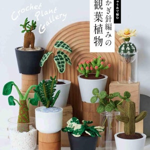 May include: A collection of crocheted plants in various colors and styles, including a cactus, a succulent, and a fern. The plants are displayed in small white pots on a wooden surface. The text "Crochet Plant Gallery" is written in black letters on a white background.
