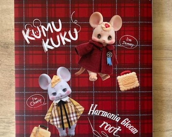 Puede incluir: Una portada de revista con dos adorables muñecas ratón vestidas con atuendos de cuadros y rojos. La revista se titula "Dollybird" y las muñecas se llaman "Kumu Kuku" y "Jammy". La portada de la revista tiene un fondo de cuadros rojos y blancos.