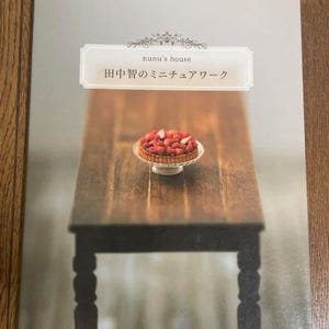 May include: A book cover featuring a miniature scene. The cover has the text "nunu's house" and Japanese text. A miniature wooden table holds a small tart topped with strawberries. The book is part of the "Handmade Series" and published by Gakken.