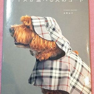 Può includere: Una copertina di libro con un cane marrone e bianco che indossa un impermeabile con cappuccio a quadri con un motivo a quadri bianchi e grigi. Il titolo del libro è "Taglie per cani da piccolo a extra grande" in giapponese. Il nome dell'autore è Yoshiko Mizuno in giapponese.