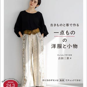Op de afbeelding: Een boekcover met een vrouw in een zwarte top en een broek met patroon. De Japanse tekst luidt "Unieke westerse kleding en accessoires gemaakt van oude dingen en riemen". De cover bevat ook de tekst "DIY Soho Handmade Warehouse".