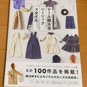 Könnte beinhalten: Ein Buch in japanischer Sprache, "Doll Clothes Complete Basic Style", mit Designs für Puppenkleidung. Das Cover zeigt verschiedene Puppenoutfits, darunter Kleider, Hosen und Hemden. Das Buch enthält 100 Muster und ist für 11-29 cm große Puppen geeignet.