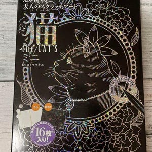 May include: A black box with a holographic silver design featuring a cat with the text "the/CAT'S" and "心を癒す 犬人のスクラッチアート" in Japanese. The box includes a silver scratch tool and a sticker that says "16枚入り!" in Japanese.