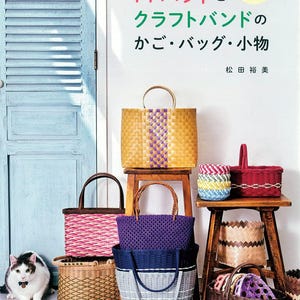 May include: A book cover with the title "PP Band and Craft Band Baskets and Small Items" in Japanese. The cover features a variety of woven baskets and bags in different colors, including yellow, purple, pink, and blue. The book is about making baskets and bags out of PP band and craft band.