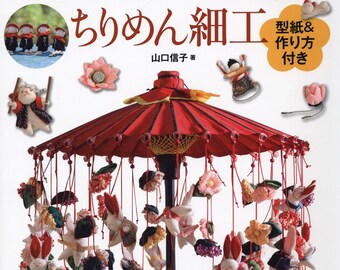 May include: A book cover featuring Japanese crafts. The title reads "First Time Tsurushi Decoration and Chirimen Crafts." The image showcases a red umbrella adorned with hanging fabric ornaments, including rabbits and flowers. Additional craft examples are displayed.