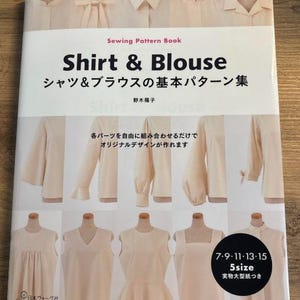 May include: A book titled "Shirt & Blouse" with a Japanese subtitle that translates to "Basic Shirt & Blouse Patterns". The cover features a variety of shirt and blouse designs in a light beige color. The book includes 5 sizes and full-size patterns.