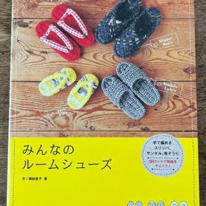 May include: A book titled "みんなの ルームシューズ" (Everyone's Room Shoes) by 市ノ瀬絵里子 (Ichinose Eriko) with a yellow cover and images of various crocheted slippers. The book cover also includes a QR code and the text "手で編める スリッパ、サンダル、布ぞうり QRコードで動画をチェック!" (Hand-knitted slippers, sandals, and fabric sandals. Check out the video with the QR code!).