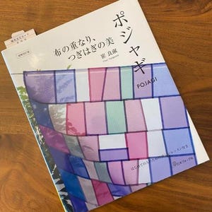 以下が含まれることがあります： 「ポジャギ」というタイトルの本。日本語のテキストと、カラフルなパッチワークのデザインが表紙に描かれています。表紙にはピンク、紫、青、緑の色合いの幾何学模様があります。左上隅には小さなタブが見えます。