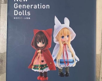 Puede incluir: Portada de la revista Dollybird con dos muñecas. La muñeca de la izquierda lleva un vestido rojo con capucha con detalles blancos y zapatos negros. La muñeca de la derecha lleva un vestido blanco con detalles azules y zapatos negros. El texto de la portada de la revista dice "New Generation Dolls" y "Dollybird vol.28".