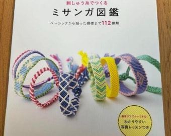 Puede incluir: Un libro japonés titulado "Guía Ilustrada Misanga", que presenta varias pulseras de la amistad coloridas. La portada muestra el título y la frase "De patrones básicos a intrincados, 112 tipos". Las pulseras son de varios colores y diseños.