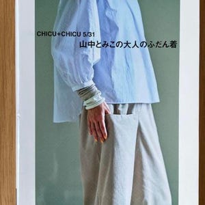 Puede incluir: Una portada de libro con una camisa azul claro y pantalones beige. El título del libro es "CHICU+CHICU 5/31 山中とみこの大人のふだん着".