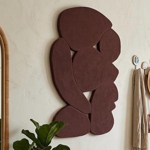 May include: A warm, inviting entryway with a wooden bench, woven baskets, and a large, abstract wall art piece in shades of brown. A large mirror and a wooden door with a woven panel add to the natural, earthy aesthetic. Plants and a woven rug complete the decor.