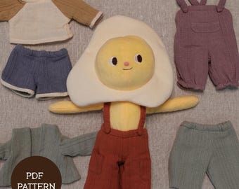 Puede incluir: Un juguete de peluche con forma de huevo frito con varios conjuntos. Los conjuntos incluyen una camiseta raglán marrón y crema, pantalones cortos azules, un mono morado, una chaqueta verde y pantalones cortos verdes. El texto "PDF PATTERN" está en un círculo marrón.
