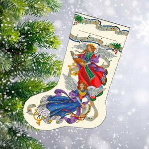 Puede incluir: Una media navideña blanca con un tema musical con tres ángeles tocando instrumentos. La media tiene un fondo crema con notas musicales y un esquema de color rojo, verde y azul.