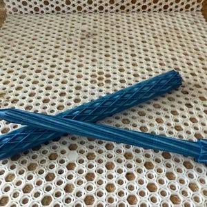 May include: Two blue pens with a diamond pattern on a white background. The pens are made of a textured material and have a blue ink cartridge.