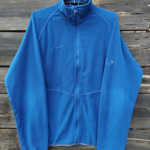 May include: A white ceramic mug with a black handle and the text "But first, coffee" in a black, handwritten-style font. The mug is on a white surface.