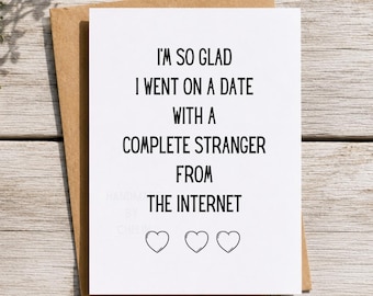 May include: A white greeting card with black text that reads: I'M SO GLAD I WENT ON A DATE WITH A COMPLETE STRANGER FROM THE INTERNET, followed by three black outlined heart icons. The card is placed on top of a brown kraft paper envelope.
