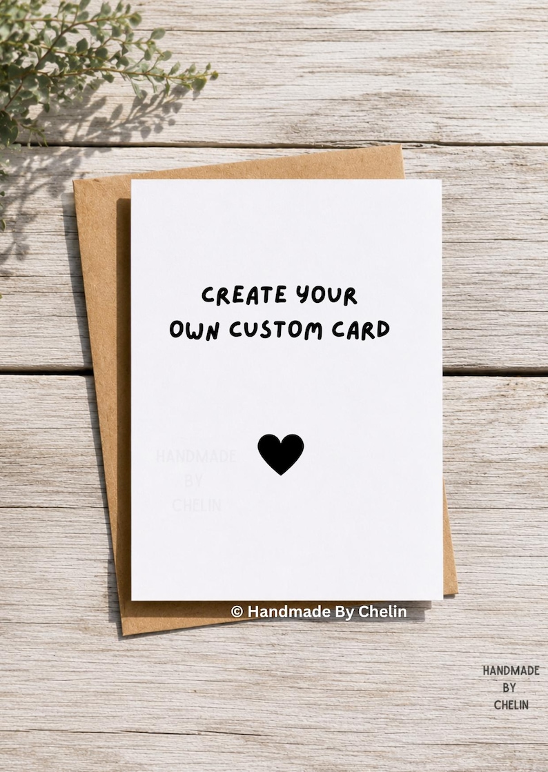 May include: A white greeting card with the black text CREATE YOUR OWN CUSTOM CARD and a small black heart icon centered below. The card is placed on top of a brown kraft paper envelope. The text Handmade By Chelin appears at the bottom.
