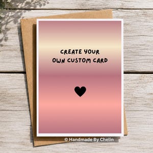 May include: A rectangular greeting card with a pink and peach gradient background. The text "CREATE YOUR OWN CUSTOM CARD" is printed in black, centered above a small black heart icon. The card is placed on top of a brown paper envelope.