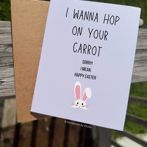 May include: A white greeting card with a brown envelope featuring the black text I WANNA HOP ON YOUR CARROT SORRY! I MEAN, HAPPY EASTER and a small illustration of a white rabbit with pink ears holding a carrot. The text Handmade By Chelin is visible.