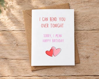 以下が含まれることがあります： I CAN BEND YOU OVER TONIGHTという赤い文字と、SORRY, I MEAN HAPPY BIRTHDAYというピンクの文字が書かれた白いグリーティングカード。テキストの下には、黒い輪郭線で描かれた赤と薄いピンクの重なり合う2つのハートのイラストがあります。