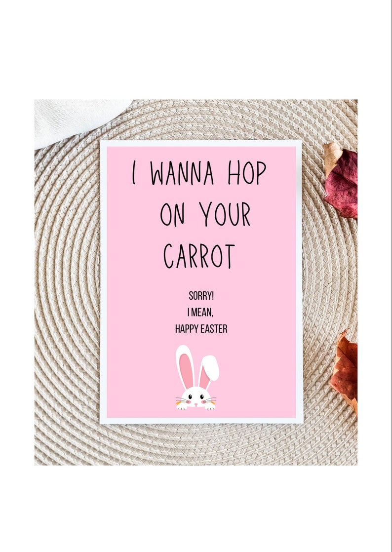 May include: A rectangular greeting card with a light pink background featuring a white rabbit illustration at the bottom. The text reads: I WANNA HOP ON YOUR CARROT, SORRY! I MEAN, HAPPY EASTER in black, sans-serif, uppercase lettering.