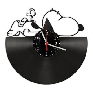 Può includere: Orologio in vinile nero con una silhouette bianca di Snoopy e Woodstock. Il quadrante dell'orologio è nero con numeri e lancette bianchi.
