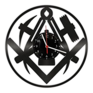 Puede incluir: Reloj de vinilo negro con un diseño en blanco y negro de una brújula, nivel y escuadra. La esfera del reloj es negra con números y manecillas blancas.