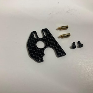 May include: A black carbon fiber motor mount with two gold screws and two black screws.