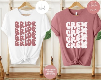 May include: Two t-shirts, one white with the word "BRIDE" repeated in a pink retro font, and one heather mauve with the word "CREW" repeated in a white retro font.
