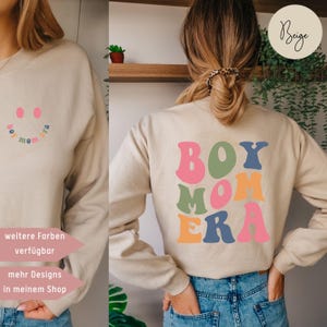 Könnte beinhalten: Beigefarbener Pullover mit dem Text "BOY MOM ERA" in bunten Blockbuchstaben. Die Buchstaben sind in den Farben Rosa, Grün, Orange und Blau gehalten.