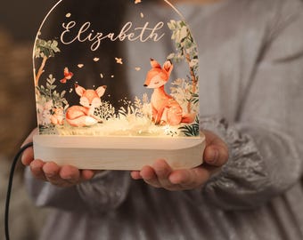 May include: A wooden night light with a clear acrylic panel featuring a woodland scene with two foxes and the name "Elizabeth" inscribed on the top. The light is illuminated with warm white LED lights.