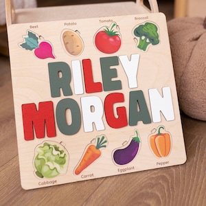 May include: Wooden puzzle with a name, Riley Morgan, and images of vegetables, including a beet, potato, tomato, broccoli, cabbage, carrot, eggplant, and pepper.