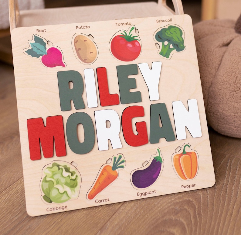 May include: Wooden puzzle with a name, Riley Morgan, and images of vegetables, including a beet, potato, tomato, broccoli, cabbage, carrot, eggplant, and pepper.