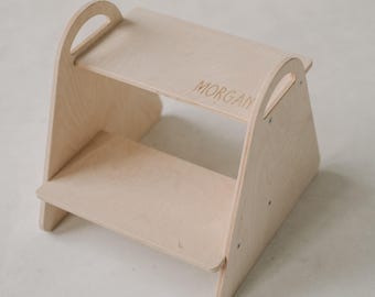 Puede incluir: Un taburete de madera clara con un asa en el escalón superior y el nombre "MORGAN" grabado en el escalón superior.