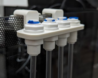 May include: A white plastic aquarium accessory with four clear tubes extending downwards. The accessory has blue accents and is designed to fit inside an aquarium. The tubes are made of clear plastic.