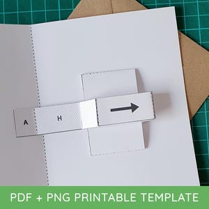 May include: A white paper pop-up card template featuring a sliding mechanism. The mechanism includes a rectangular tab with the letters A and H printed on a hatched background, connected to a white strip with a black arrow pointing to the right.