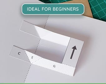 May include: A white paper craft template featuring a pop-up mechanism with dashed fold lines and labelled sections C, E, and G. The template includes a black arrow pointing upward and text that reads IDEAL FOR BEGINNERS and PDF + PNG PRINTABLE TEMPLATE.