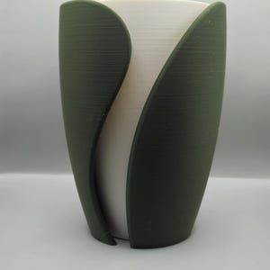 Könnte beinhalten: Ein weißer Topf mit einer grünen Außenschale. Der Topf ist tulpenförmig mit zwei Blättern auf jeder Seite.