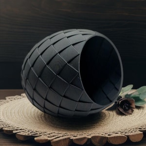 May include: A black woven basket with a round shape and a wide opening. The basket is made of a thick, textured material and has a smooth, polished finish.