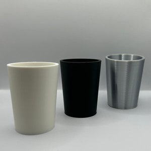 May include: Three cylindrical planters, one white, one black, and one silver.