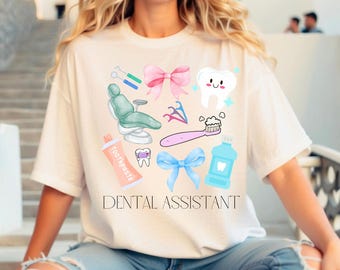 May include: White t-shirt with a watercolor design of dental tools, including a toothbrush, toothpaste, floss, and a dental chair. The text "Dental Assistant" is printed below the design.