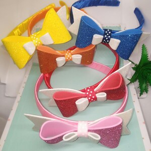 May include: Five colourful headbands with glitter bows. The bows are made of foam and have white polka dots. The headbands are made of satin.