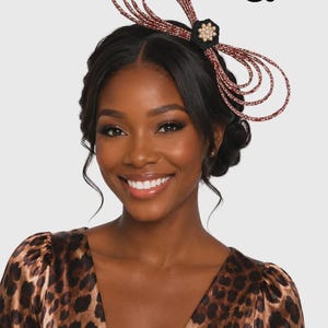 May include: A decorative headpiece featuring multiple loops of brown and white leopard print material, accented with a central black fabric flower and a cluster of small white pearls. The number 5 is visible in the upper right corner.